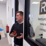 Héctor Pietri Gerente General en una oficina junto a una puerta de cristal que muestra el logotipo de Reserpax y datos de contacto